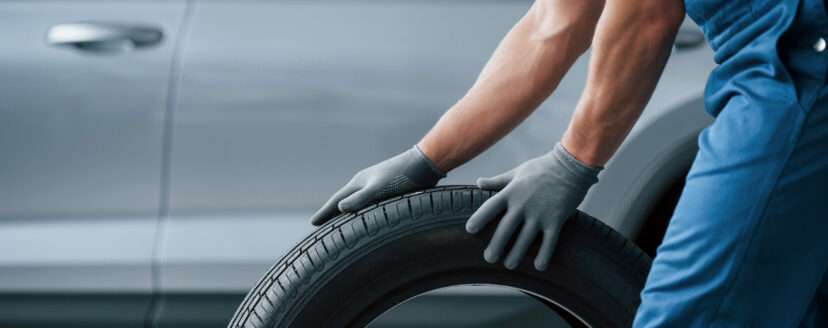 Art of transportation. Mechanic holding a tire at the repair garage. Replacement of winter and summer tires.